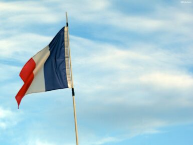 a flag flying in the wind with a blue sky in the background