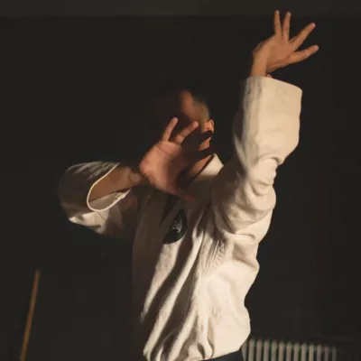 A man standing in a room holding his arms up in the air